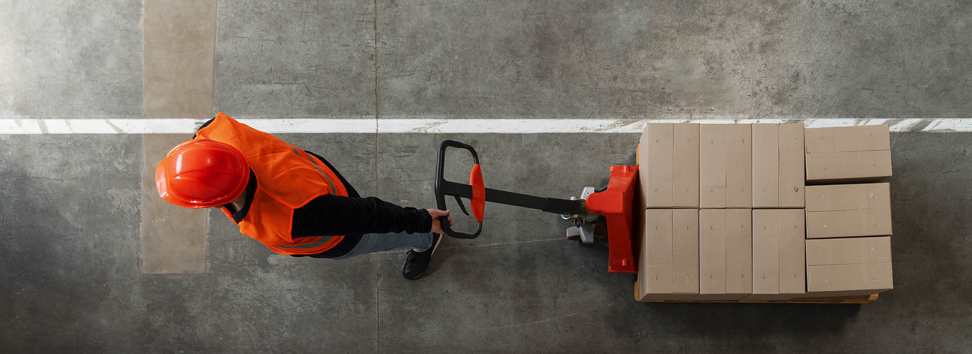 Man pulling a pallet lifter with boxes on - image attribution https://www.freepik.com/free-photo/full-shot-man-working-construction_65550091.htm