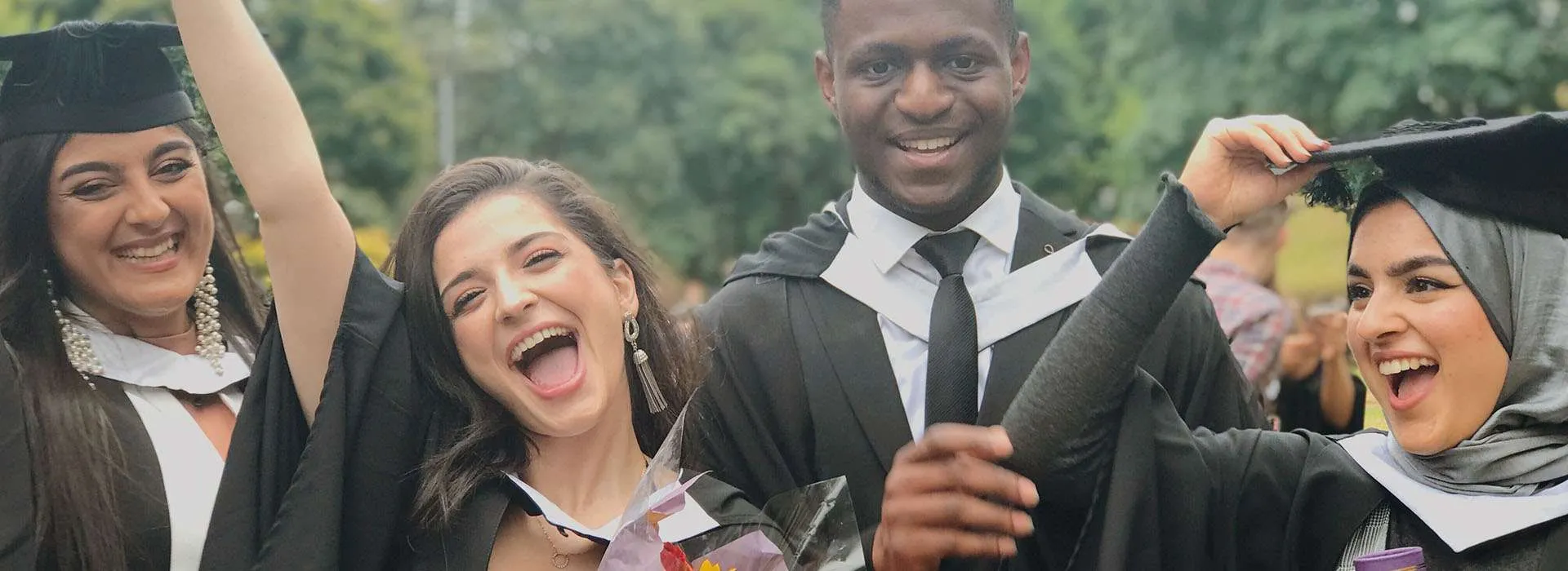 students celebrating with a bunch of flowers at graduation