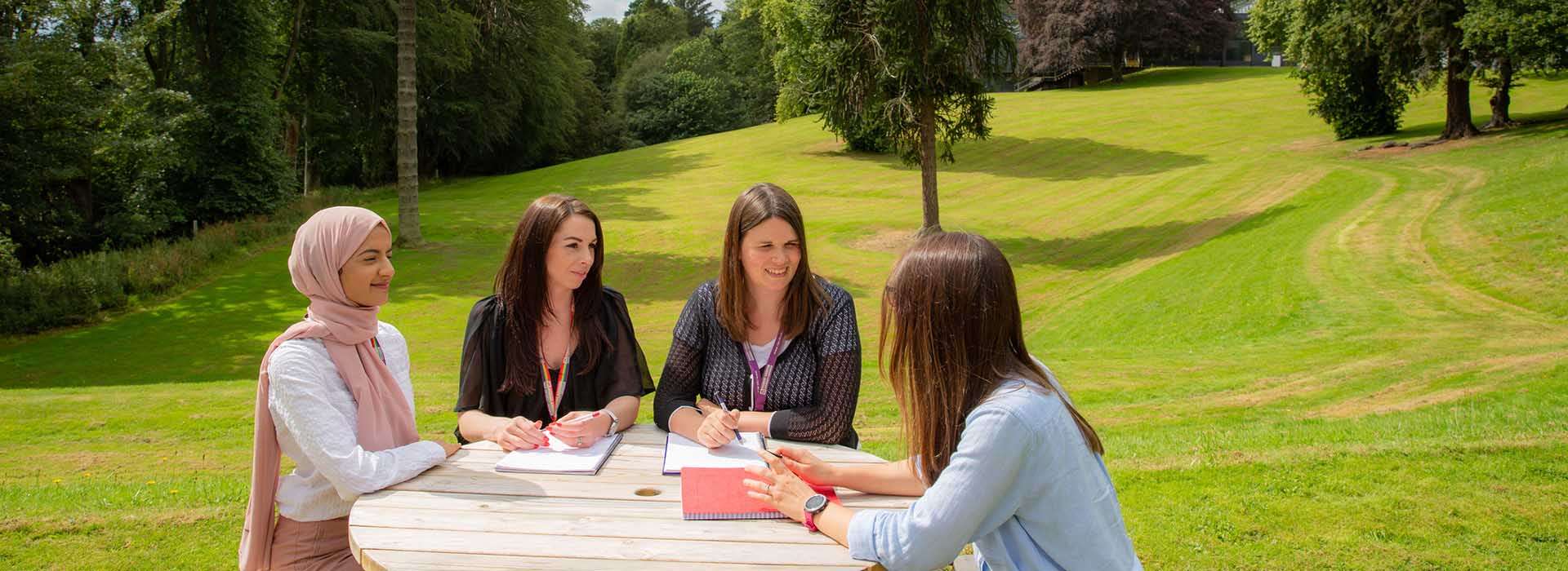 People at a picnic bench outside talking