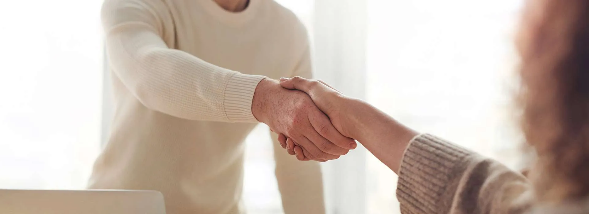 two people shaking hands over a meeting table