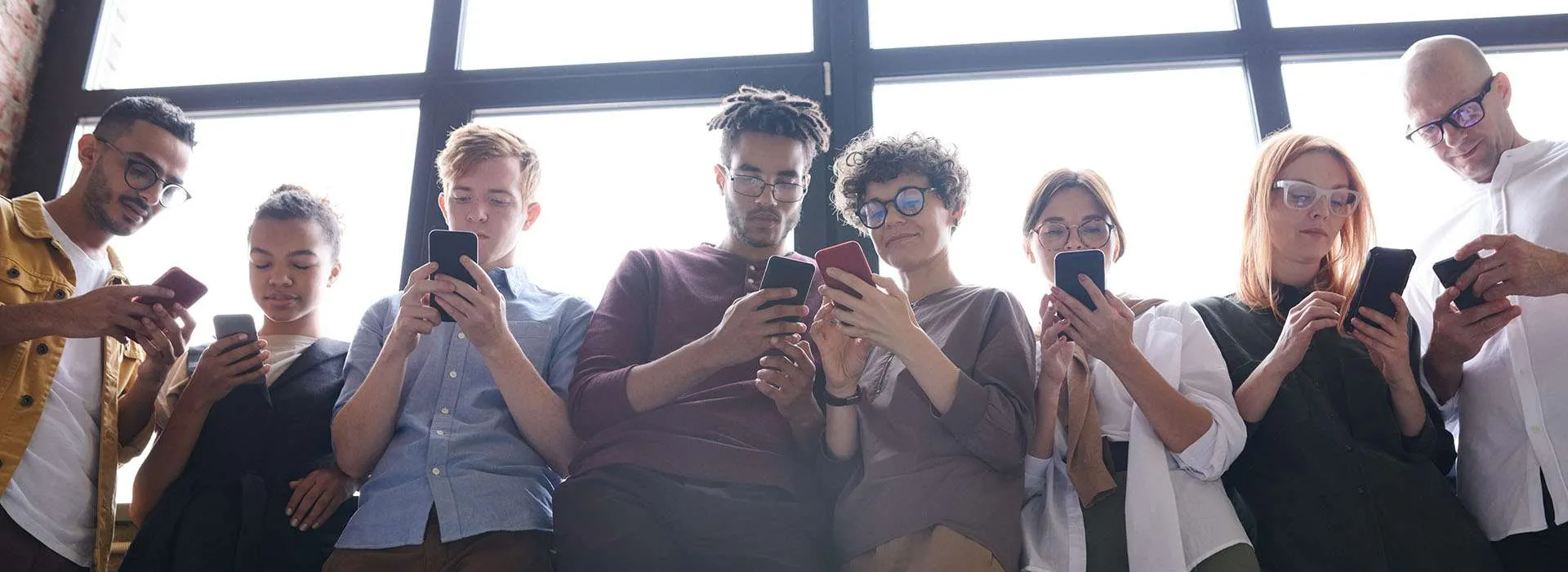 people standing next to window using their phones