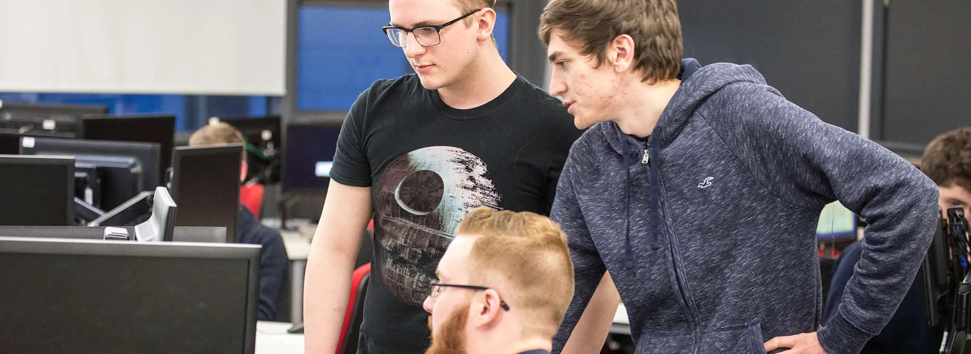 three students looking at a computer monitor together