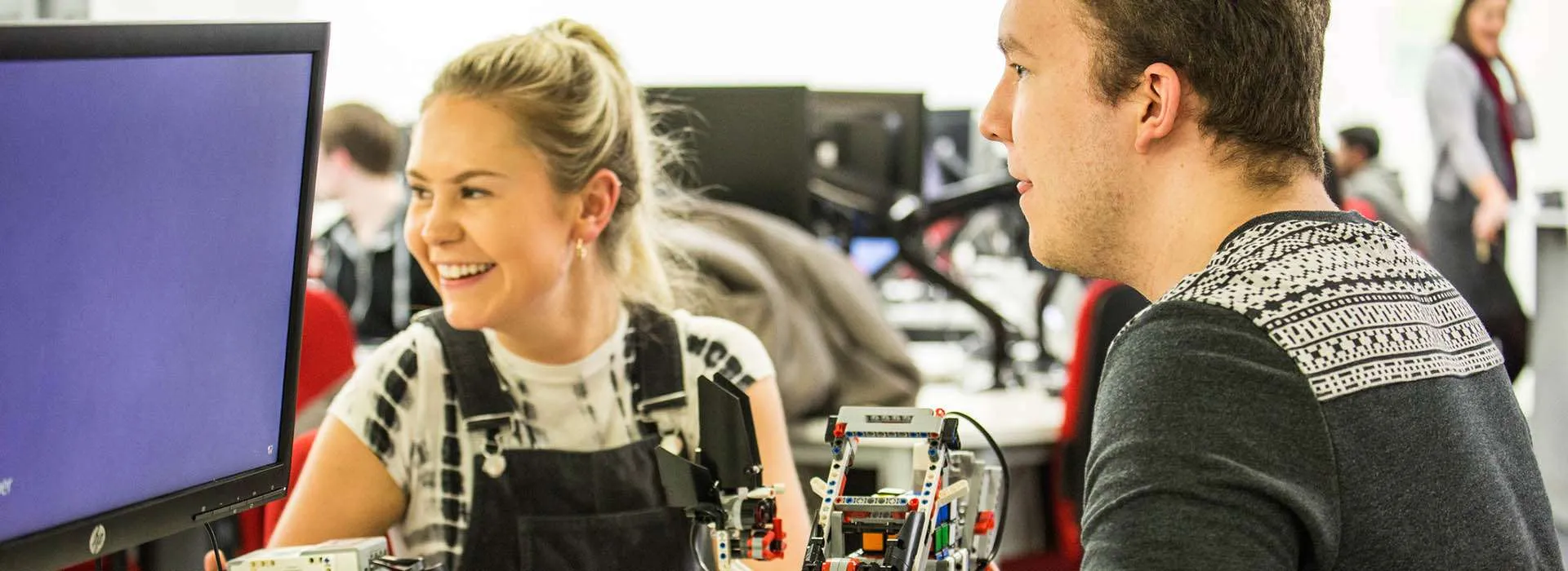 two students smiling holding robotics kits