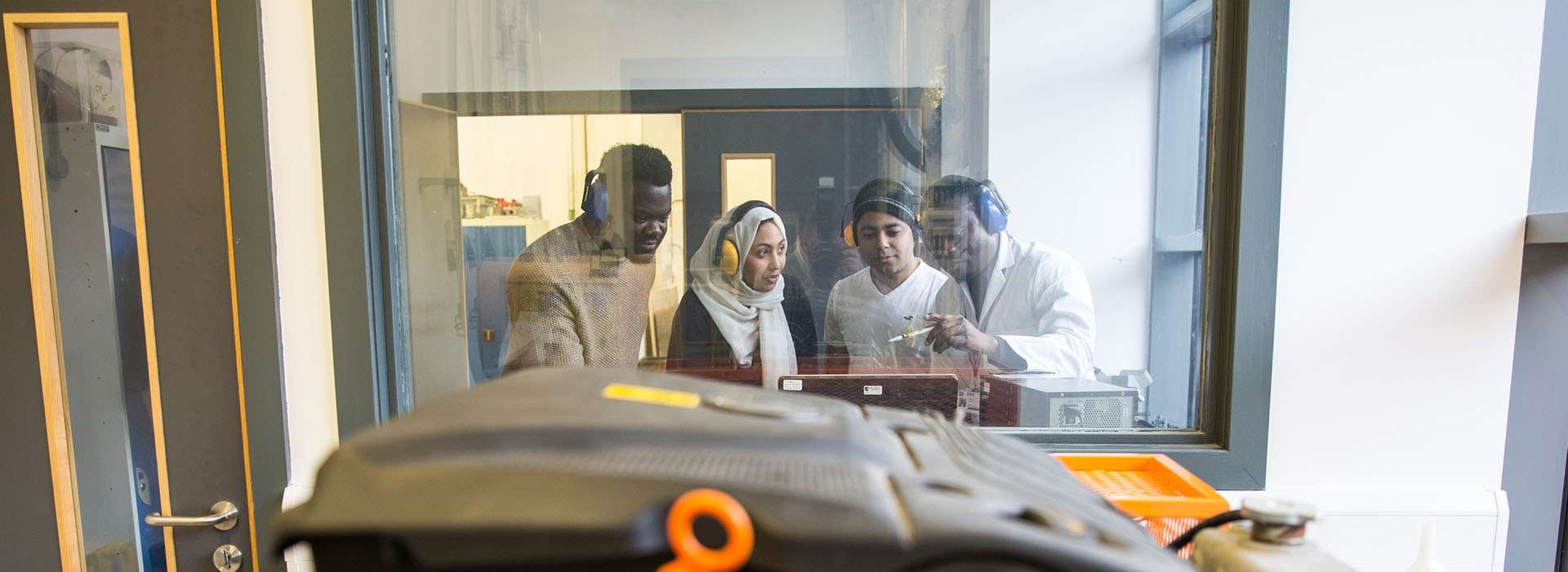 students watching engineering project from behind glass students watching engineering project from behind glass