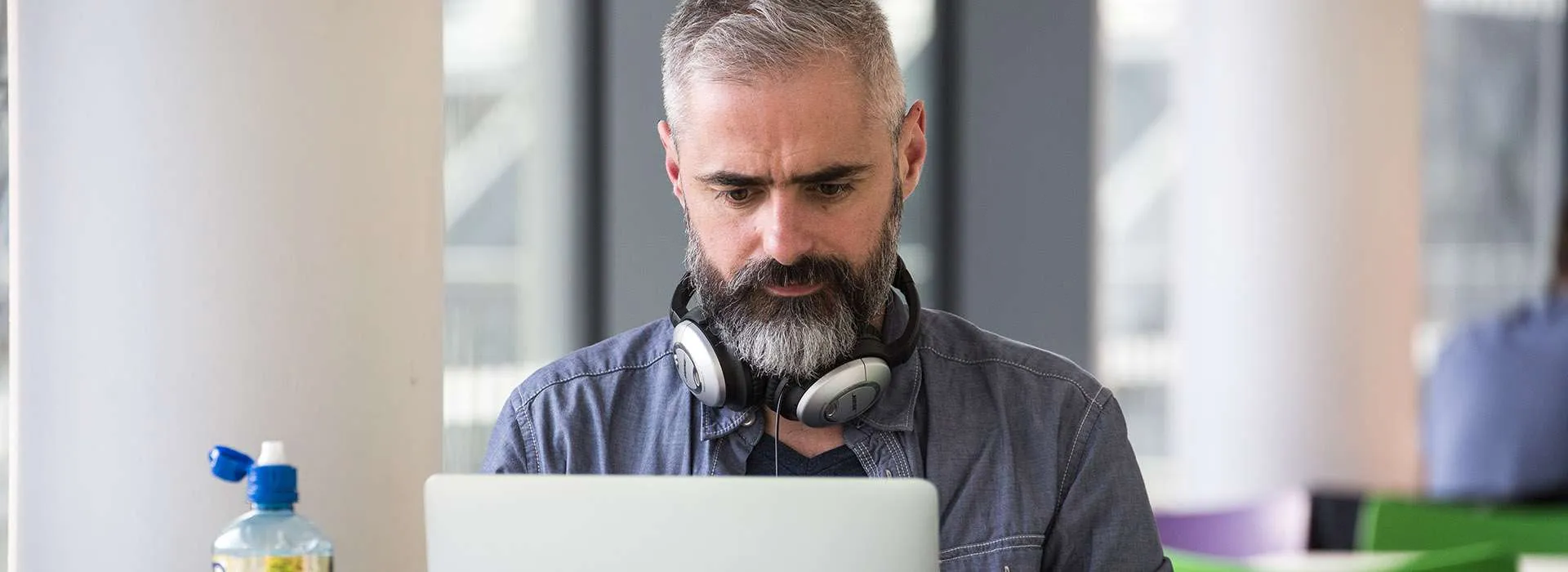 man sitting in a cafeteria looking at his laptop