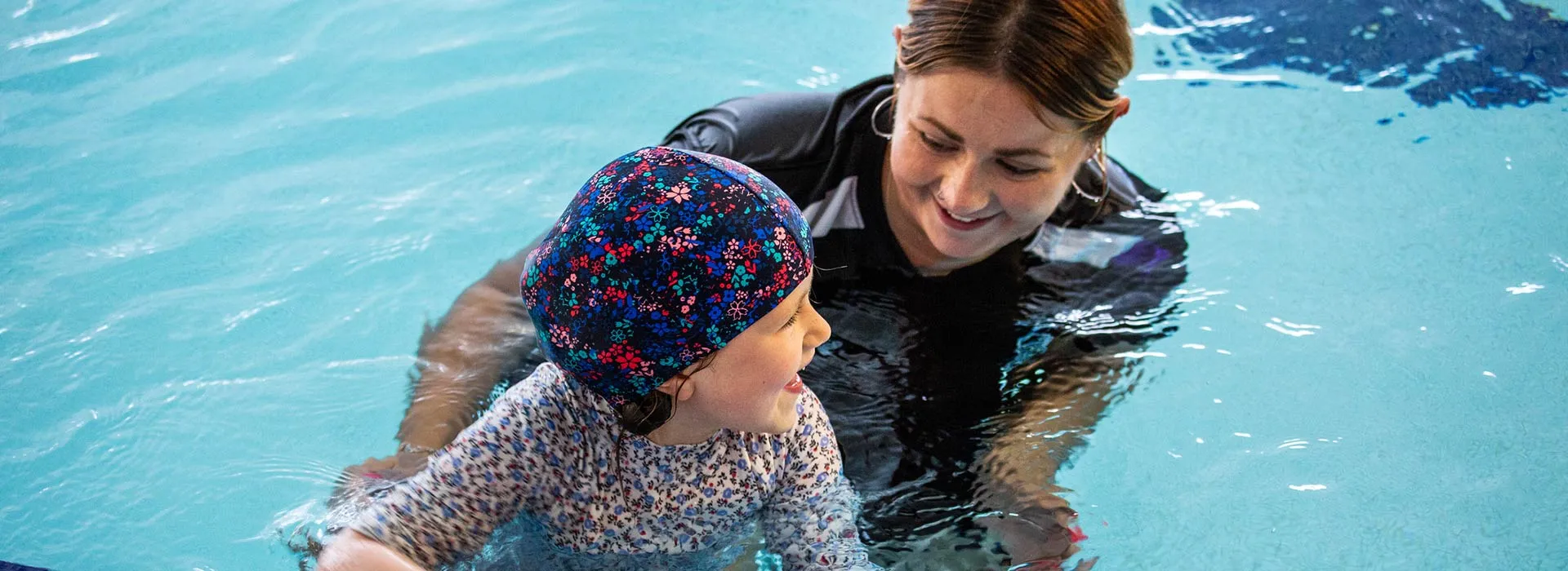 swimming instructor teaching a child in a pool