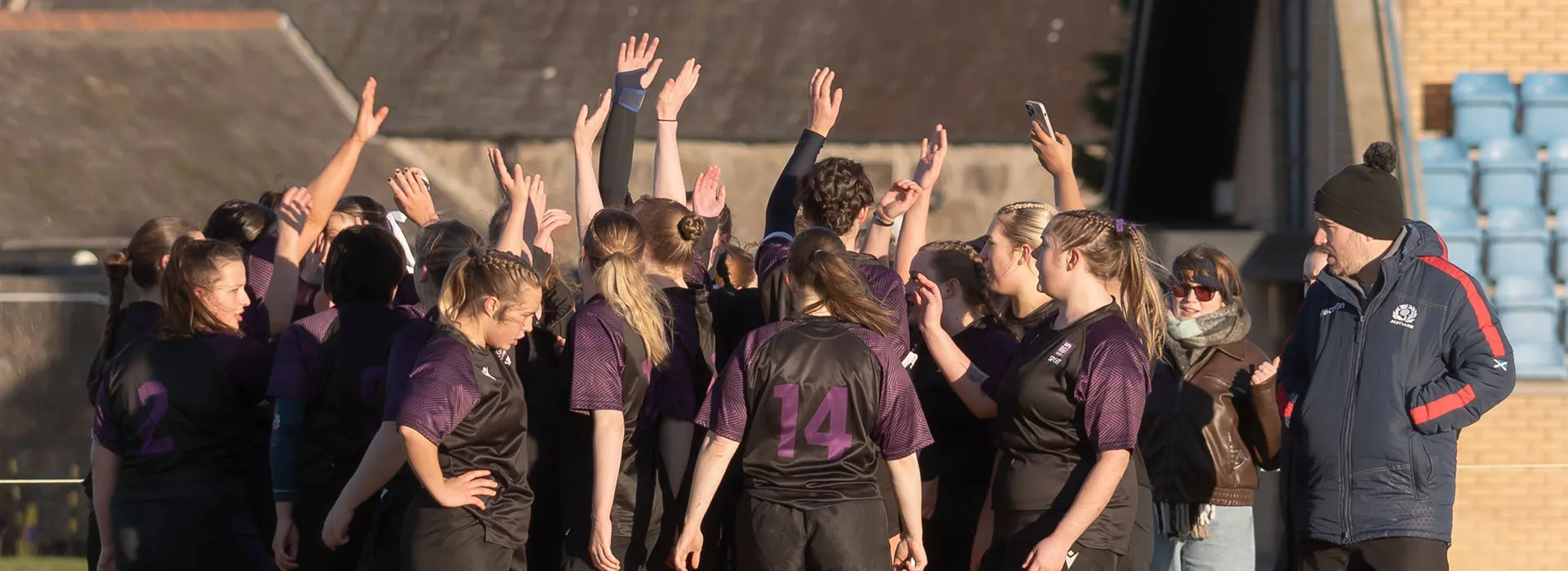 Group of students with their arms up during a sports club match