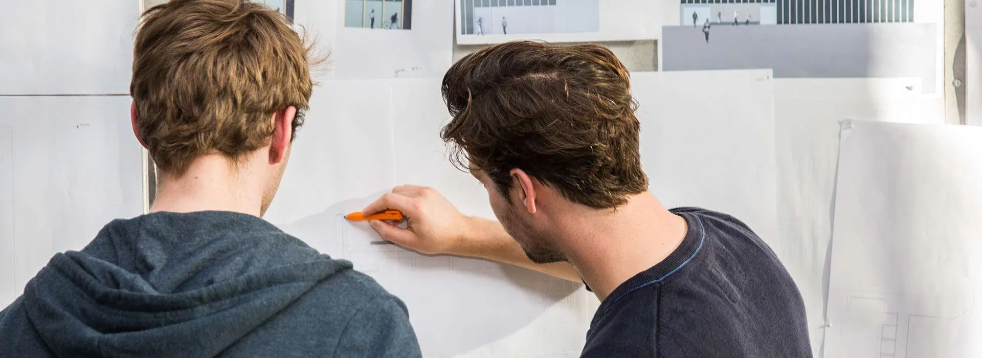 two people looking at technical drawing on a wall