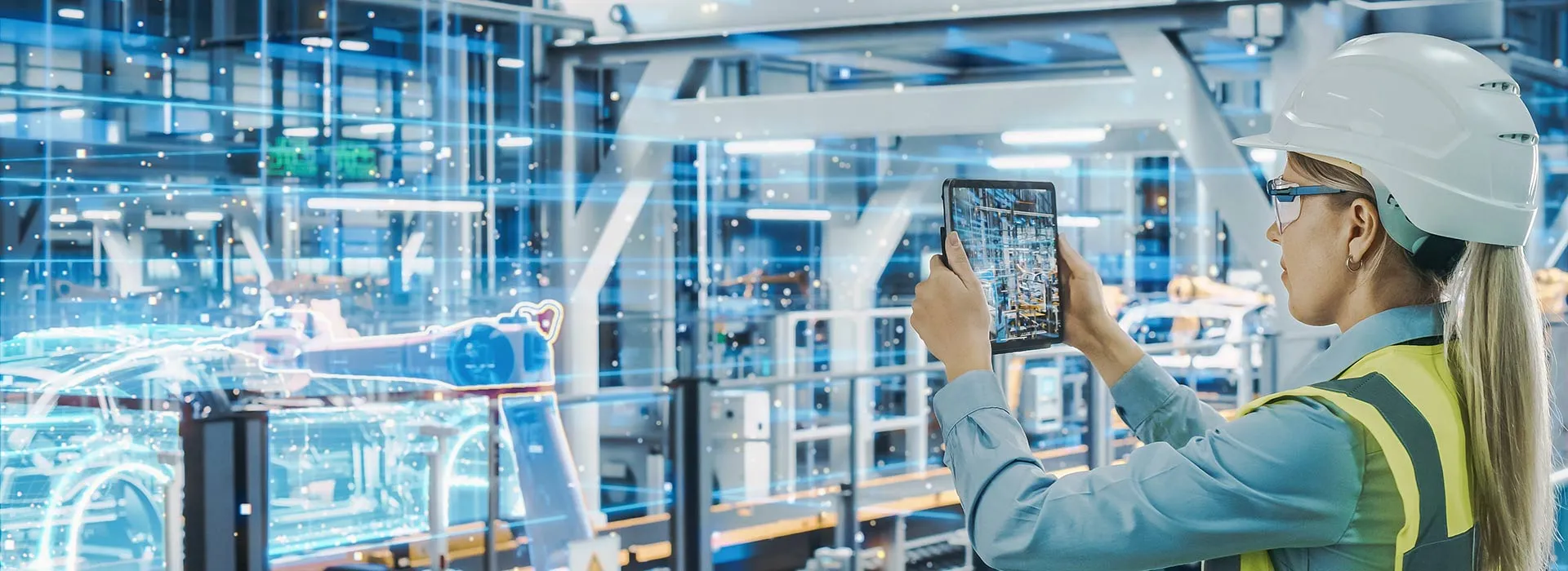 Person in hard hat and safety jacket looking at engineering through a mobile device