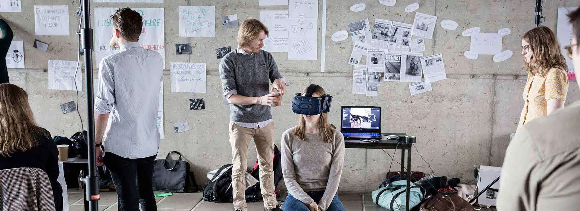 people in a creative workspace, one is wearing a VR headset