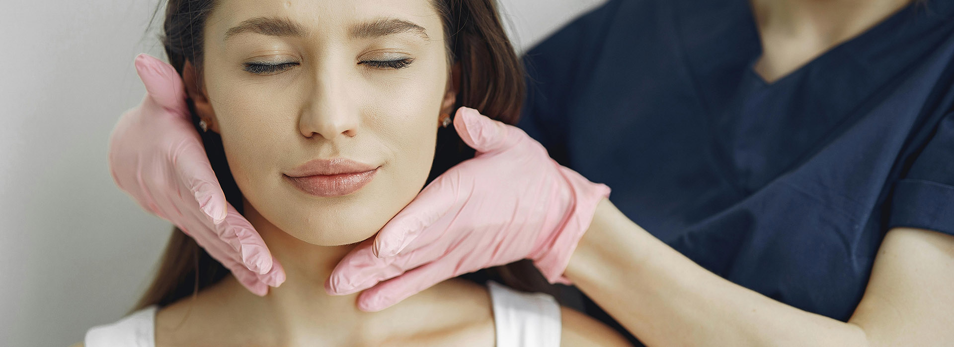 person with medical gloves on touching another persons face