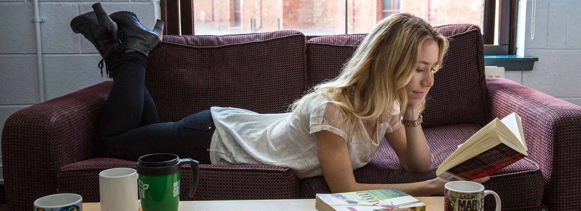 student reading a book on the sofa in student accommodation
