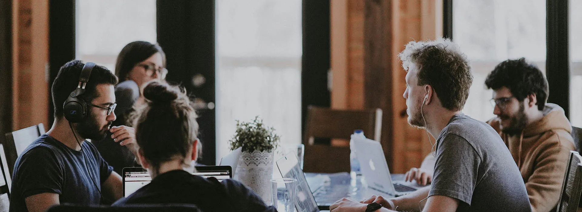 people wearing headphones using laptops around a table