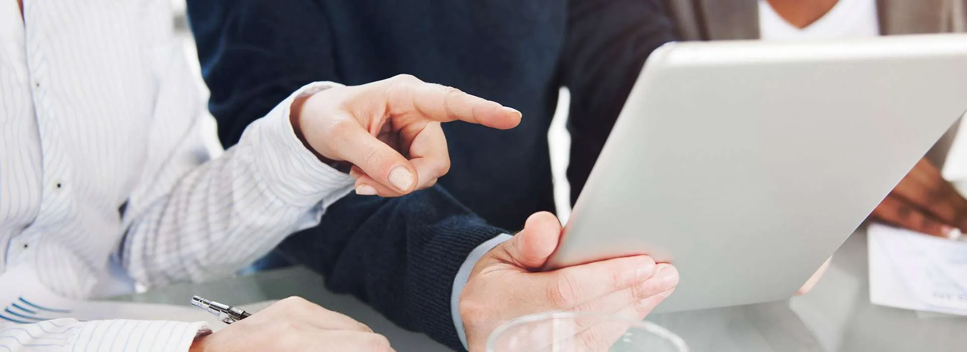 people chatting and pointing at a tablet