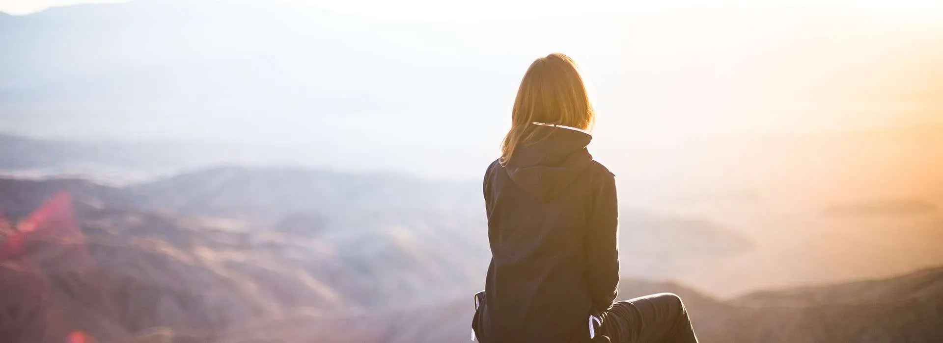 girl on a mountain looking at the sun rise