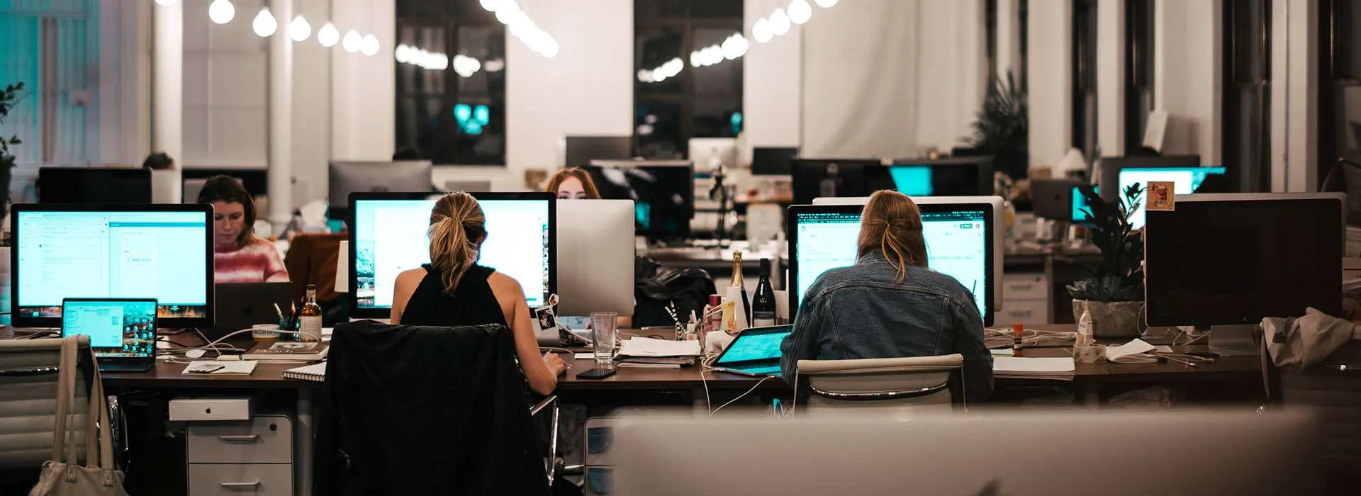 people sitting in front of screens in a computer lab