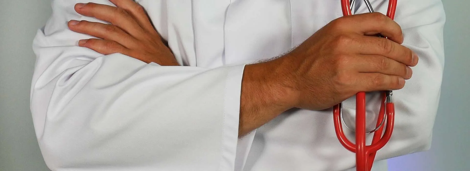 a person in a white coat holding a red stethoscope