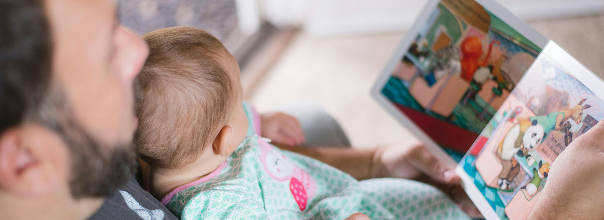 Man holding a baby and reading a book