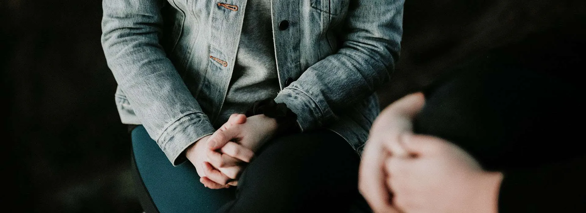 person's hands clasped in front of them in a conversation