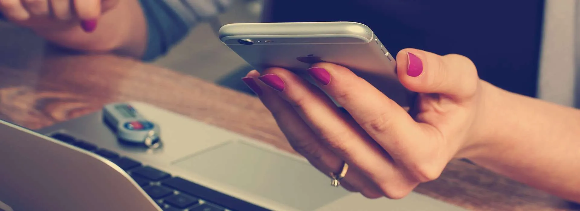 woman holding phone next to computer