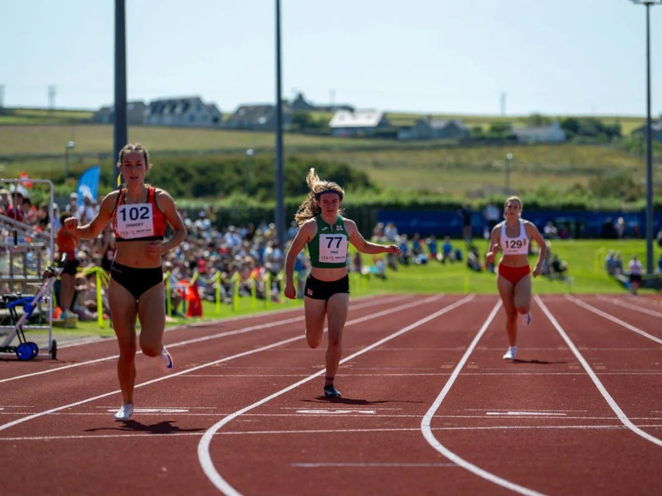 Athletes running along a red track on a sunny day