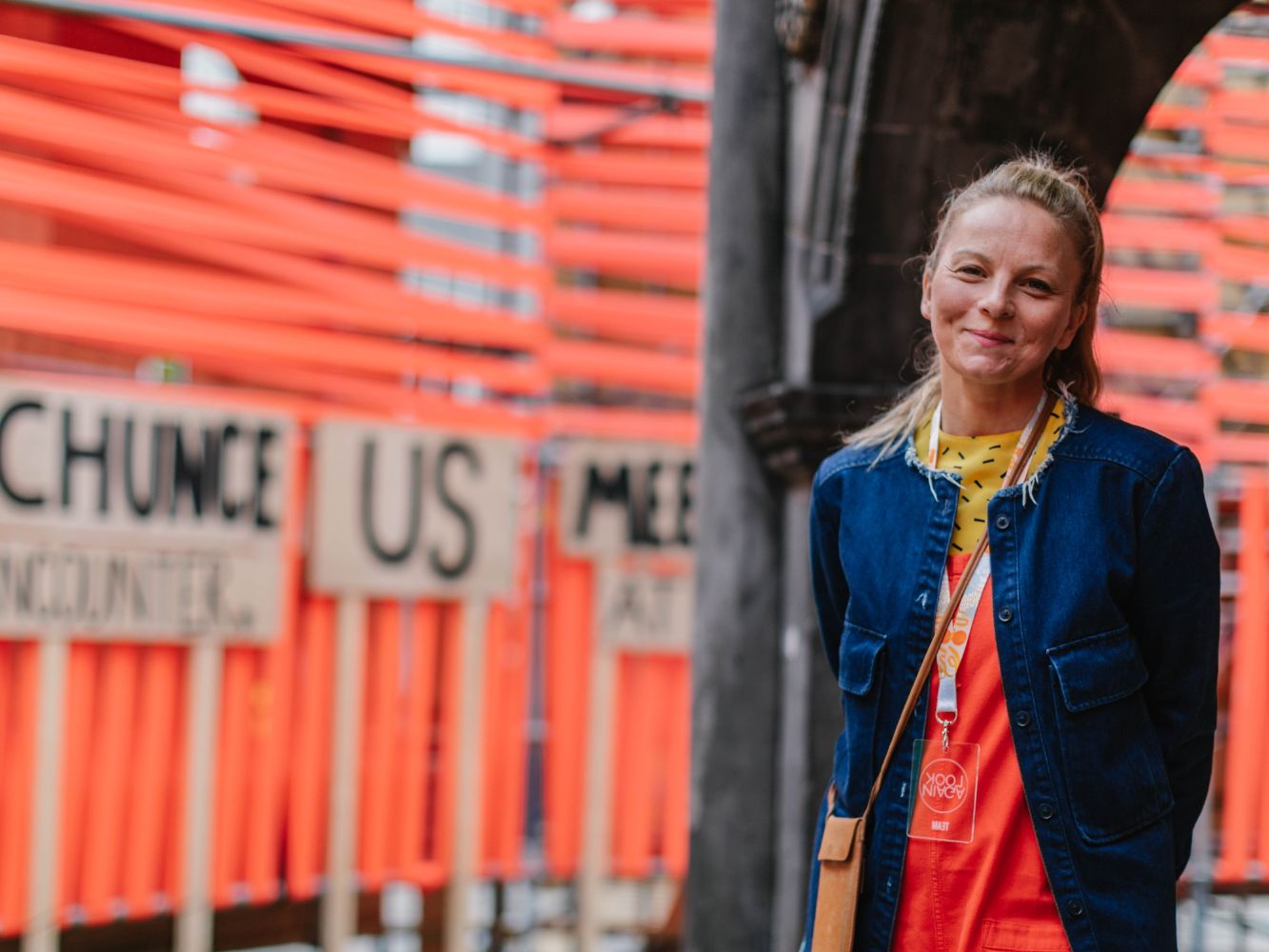 Image shows Sally Reaper in front of the Love at First Sight exhibition by Morag Myerscough, with text from Jo Gilbert’s poem, from Look Again Festival 2019 - Photo by Grant Anderson