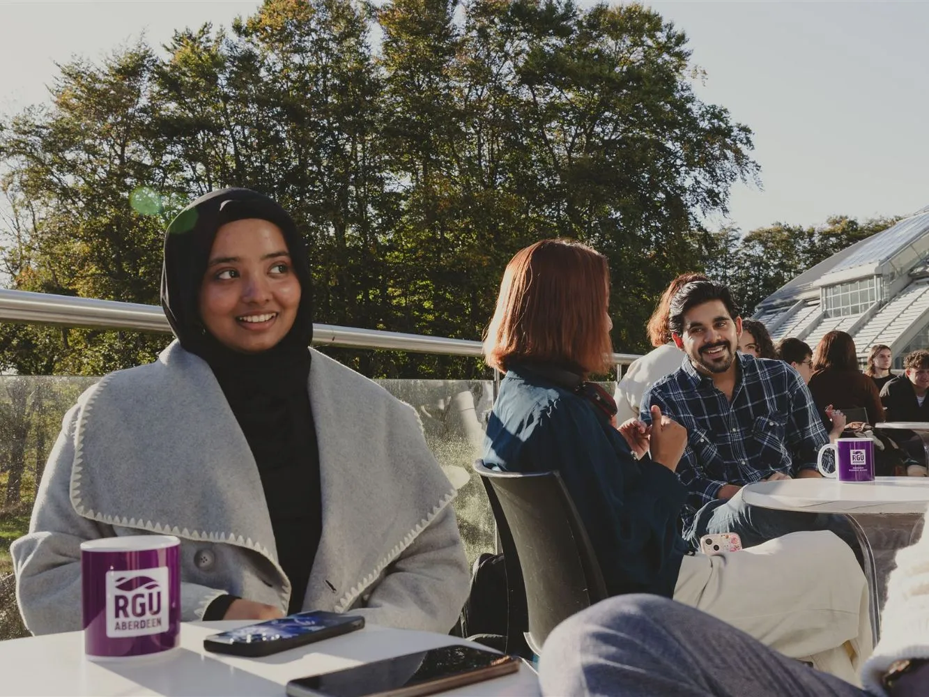 RGU students drinking from University mugs on a balcony