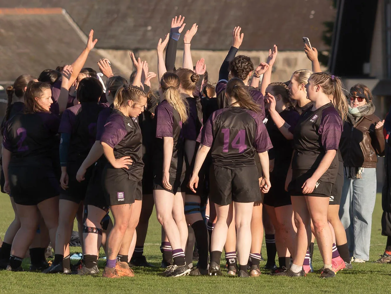 Group of students with their arms up during a sports club match