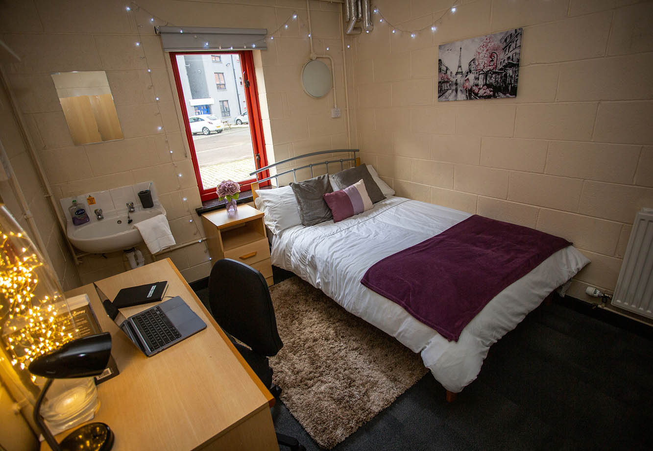 Bedroom featuring a double bed, fairy lights, a sink and a desk