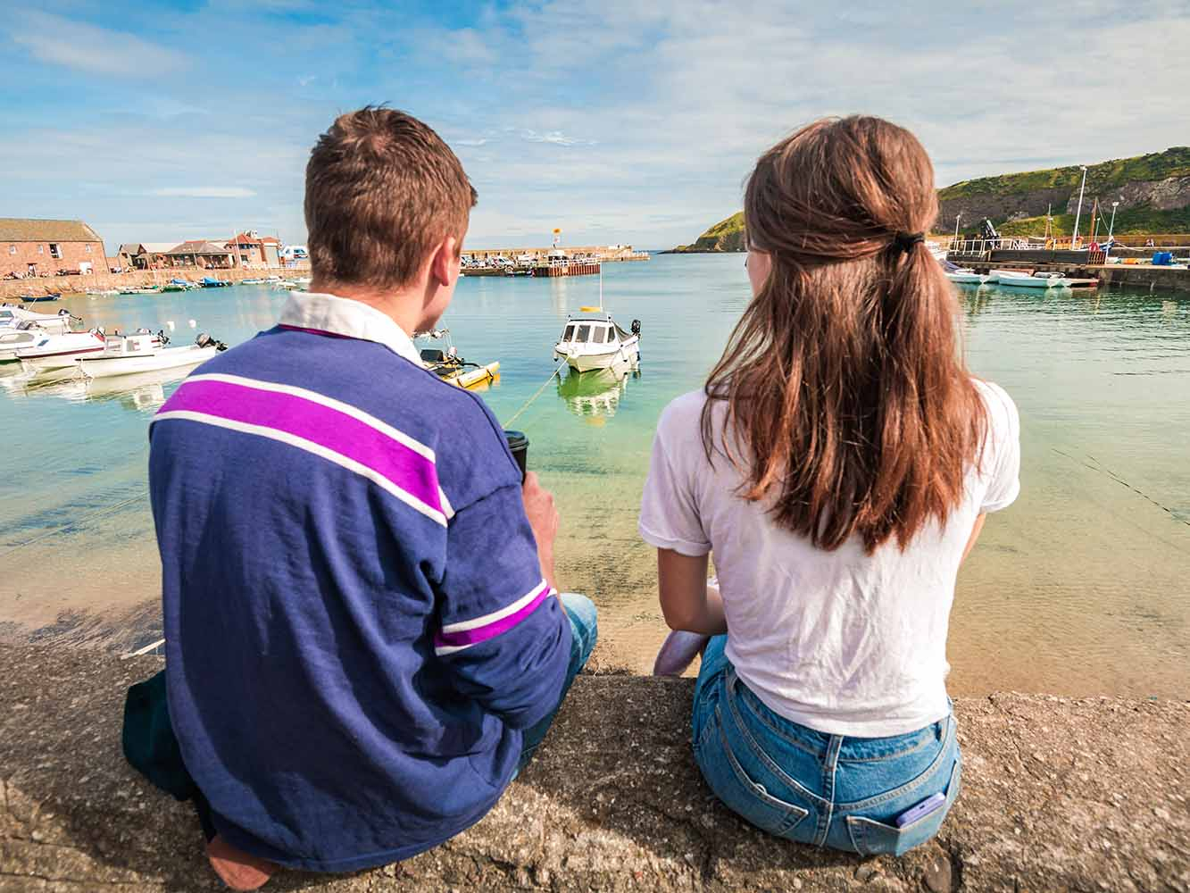 Two people sit looking onto a harbour