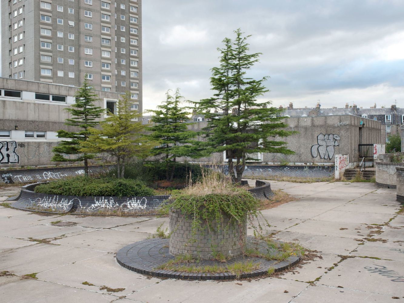 The current Upper Denburn Gardens scene shows overgrown plants, graffiti and uncared for concrete