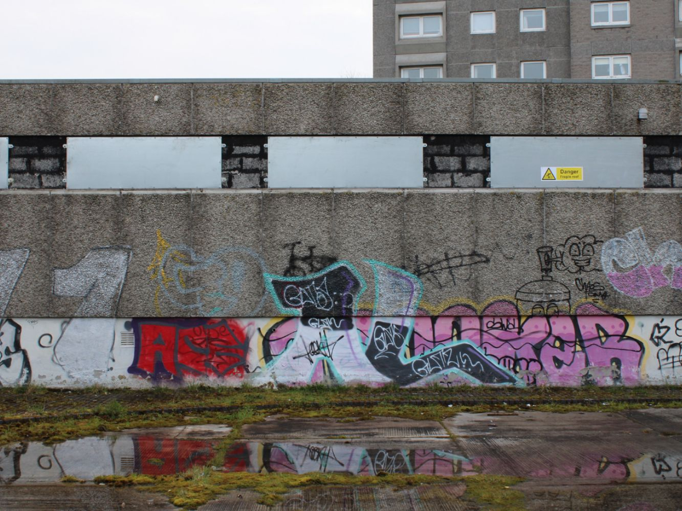 The current Upper Denburn Gardens scene shows overgrown plants, graffiti and uncared for concrete