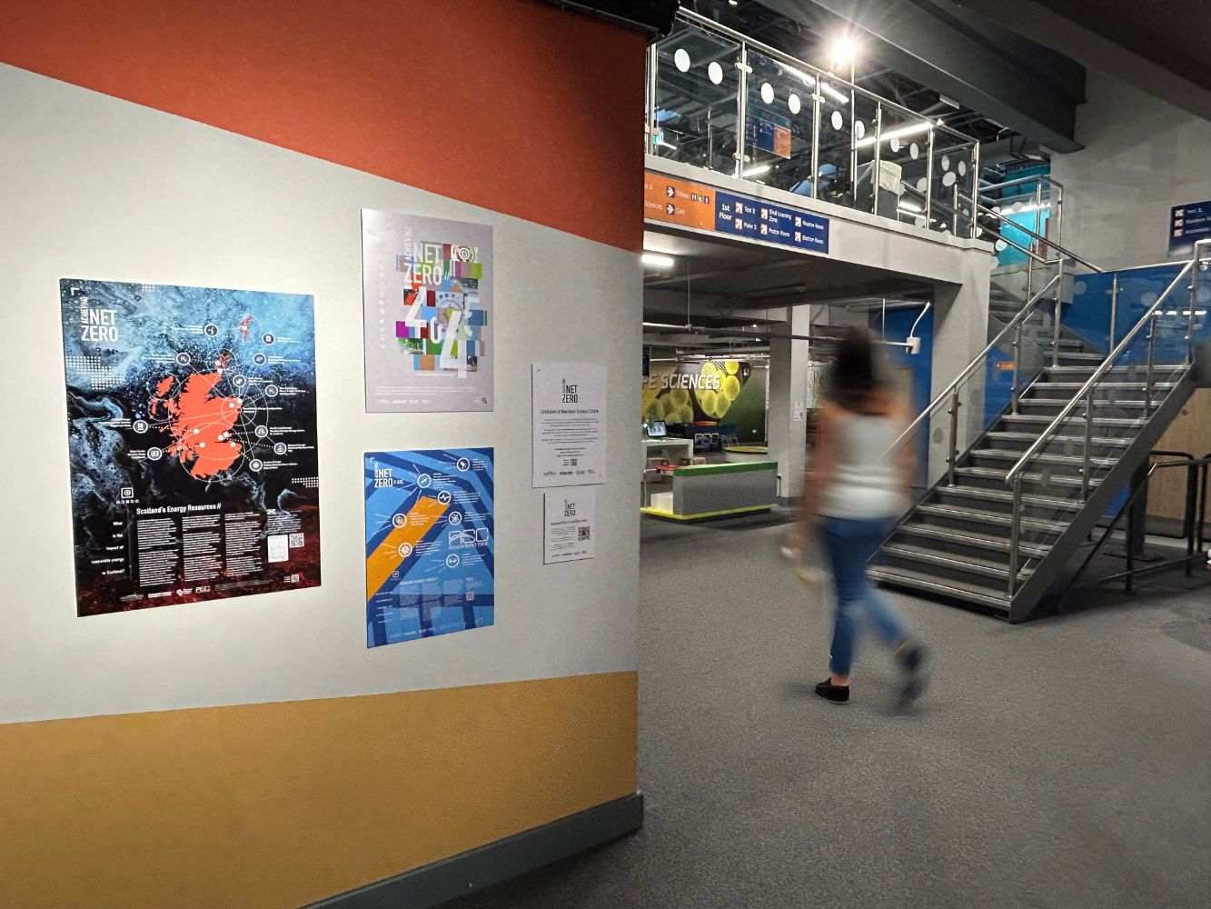 The posters in situ in Aberdeen Science Centre with blurred passers by in the background