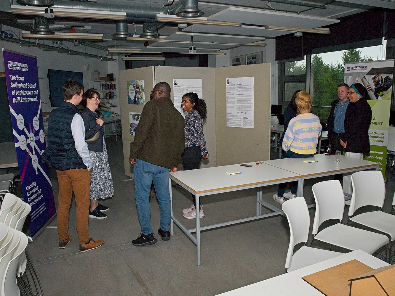 people chatting by architectural models and display boards