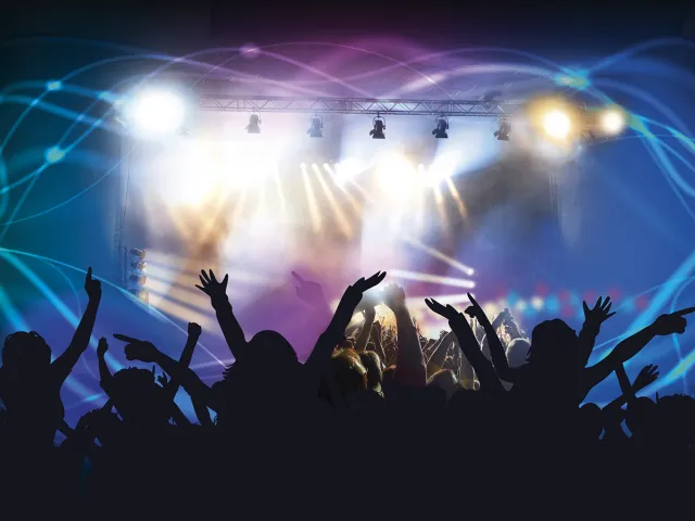 concert attendees waving their hands in front of a lit stage