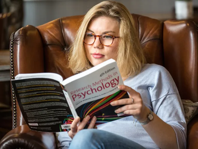woman in a buttoned chair reading a psychology book