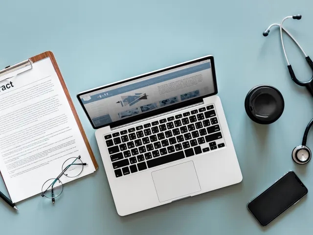 desk with laptop, documents and stethoscope