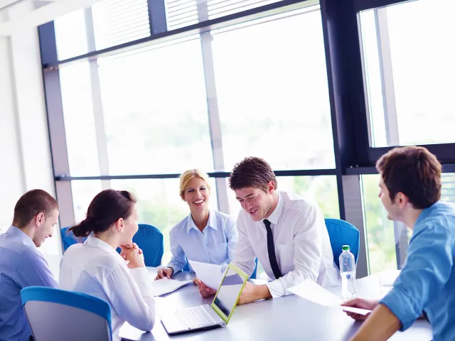 people wearing formal shirts having a meeting around a table