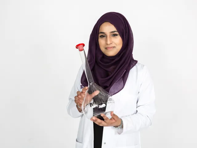 woman wearing headscarf holding large beaker