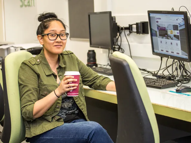 student sitting at a computer with a coffee