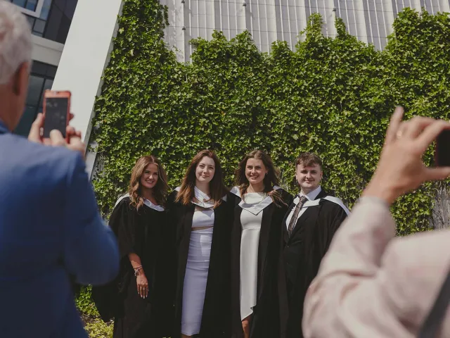 4 graduates getting photographs taken outside P&J Live
