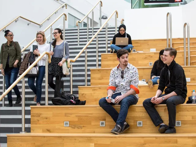 students chatting on large wooden steps
