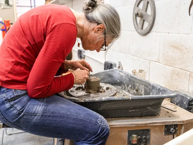 Student learning how to throw pottery
