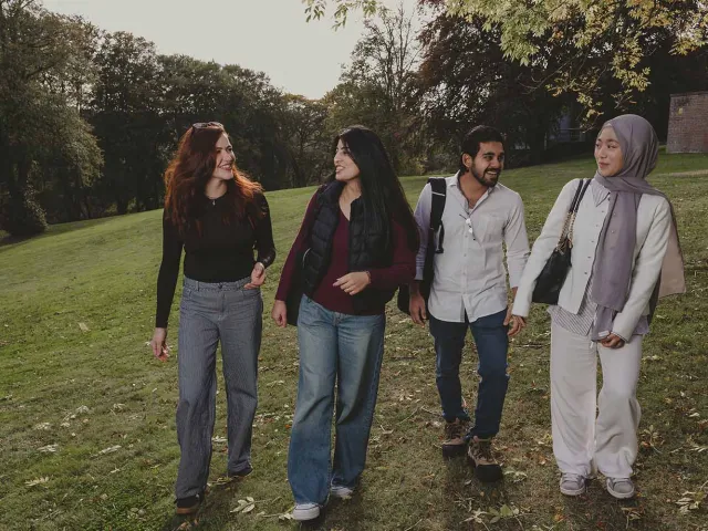 Four students walk in green area on RGU campus