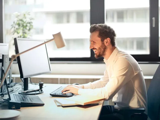 man smiling at computer screen