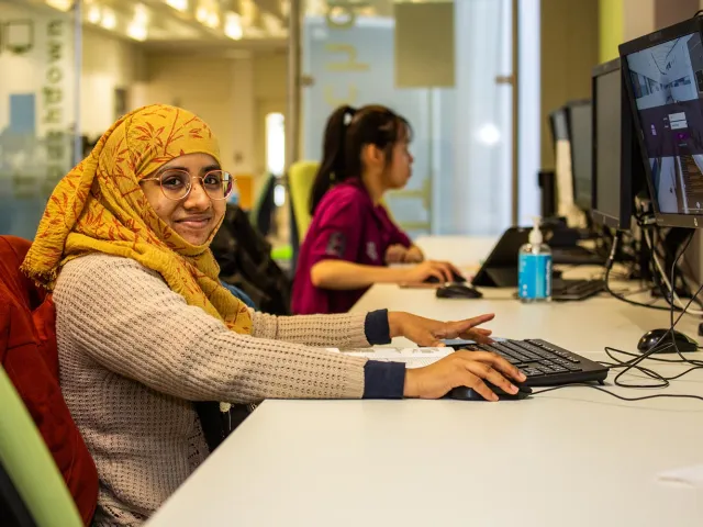 female student wearing a headscarf on a computer
