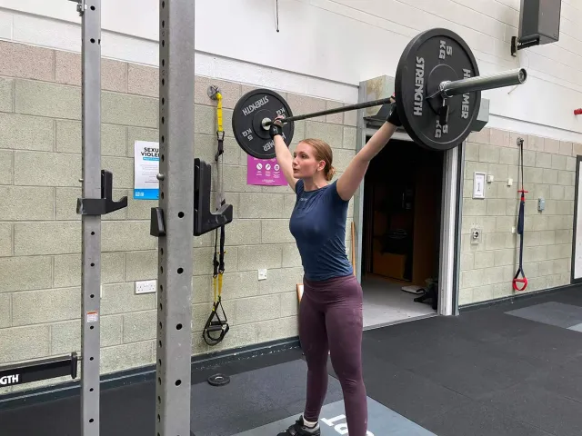 female student lifting barbell