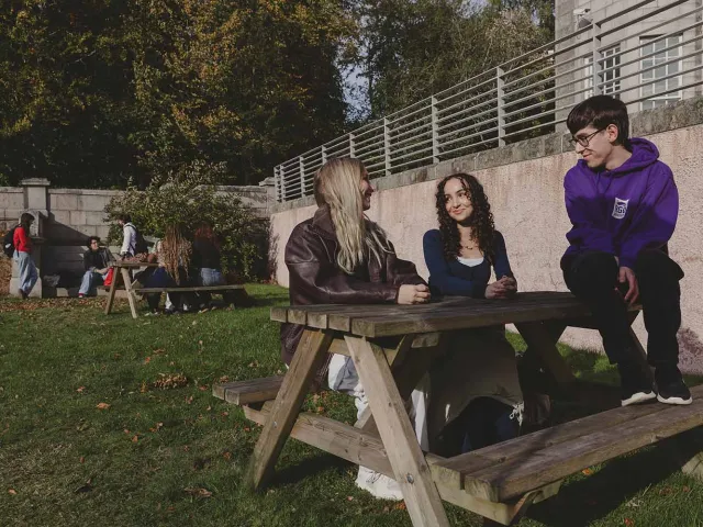 3 students sit at bench on RGU campus