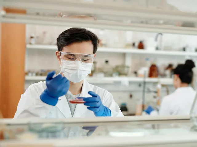 person wearing a mask in a lab using equiptment