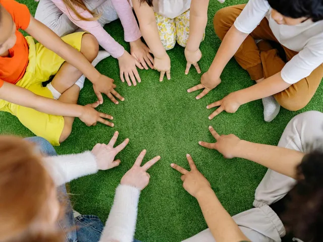 Children sitting in a circle with their hands together in the middle